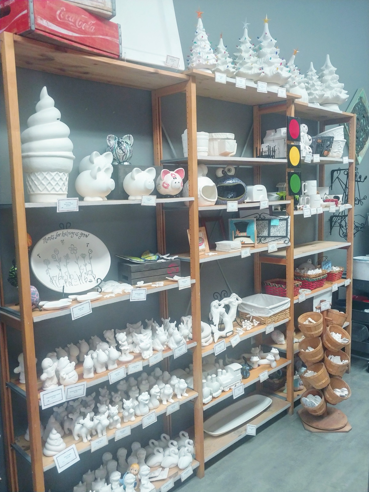 Shelves lined with unpainted white bisque pottery pieces ready to be chosen at Amazing Glaze