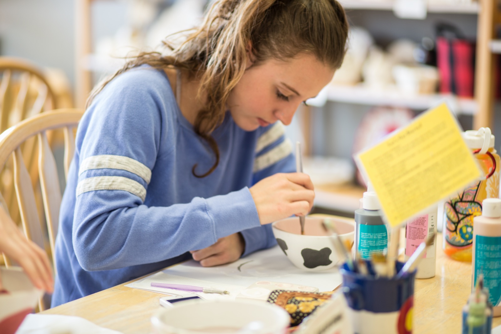 A guest smiling while glazing a ceramic piece at Amazing Glaze
