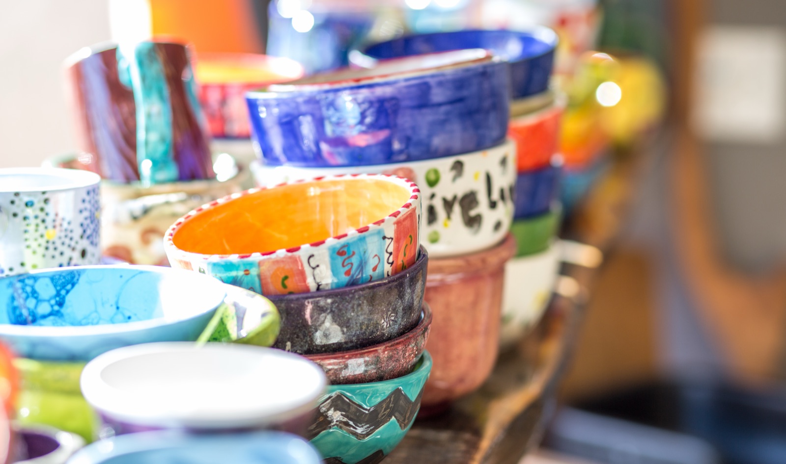 Colorful hand-painted bowls and dishes finished by Amazing Glaze guests