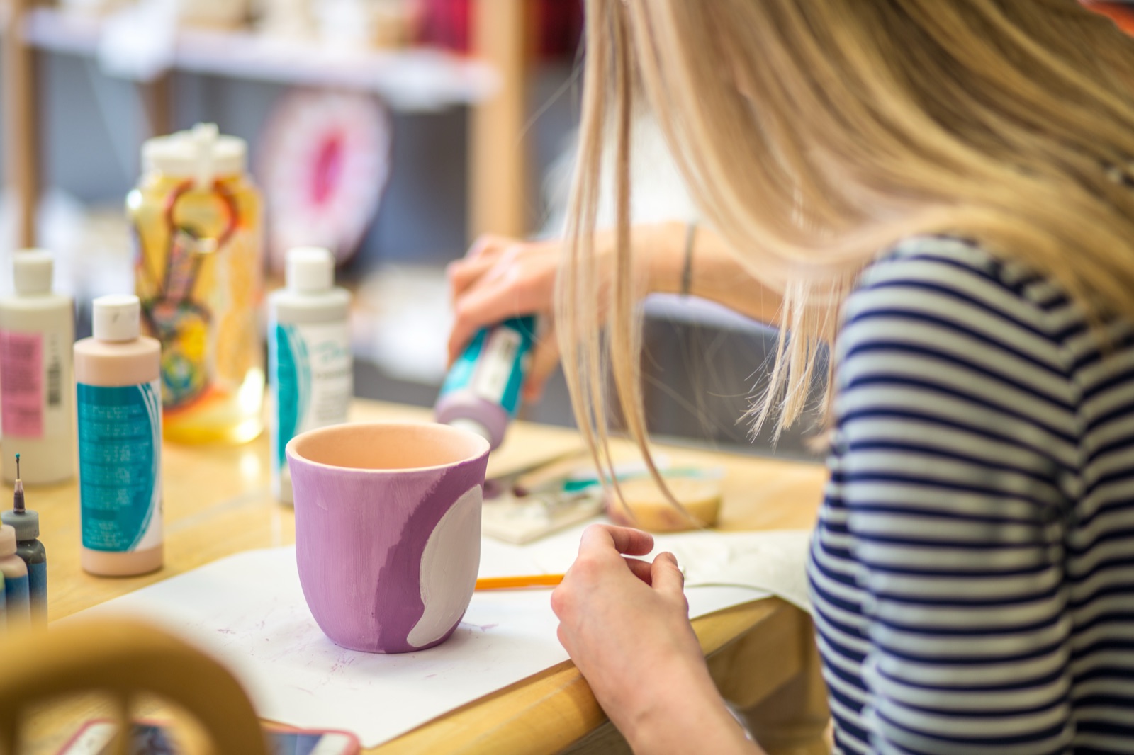 Two guests painting ceramic pieces together at Amazing Glaze studio